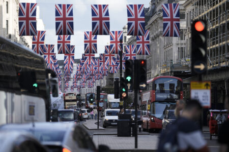 Traffic moves through the decorated Regent Street in central London Friday, May 5, 2023. The Coronation of King Charles III will take place at Westminster Abbey on May 6.