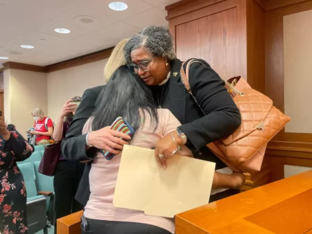 Gloria Cazares, the mother of 9-year-old Uvalde shooting victim Jackie Cazares, is hugged by Rep. Rhetta Bowers, D-Garland, right, and Rep. Vikki Goodwin, D-Austin, left, after a House panel advanced on Monday, May 8, 2023 a measure that would raise to 21 the minimum age to purchase a semi-automatic weapon.