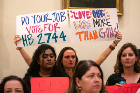 Woman holding a sign saying, "Love our kids more than guns" during a demonstration in the Texas Capitol Rotunda on May 8, 2023 demanding for an age increase to AR-15. Patricai Lim/KUT