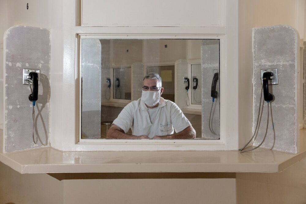 A man behind glass in a visitation room in a Texas prison