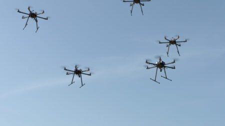 five drones flying in a blue sky