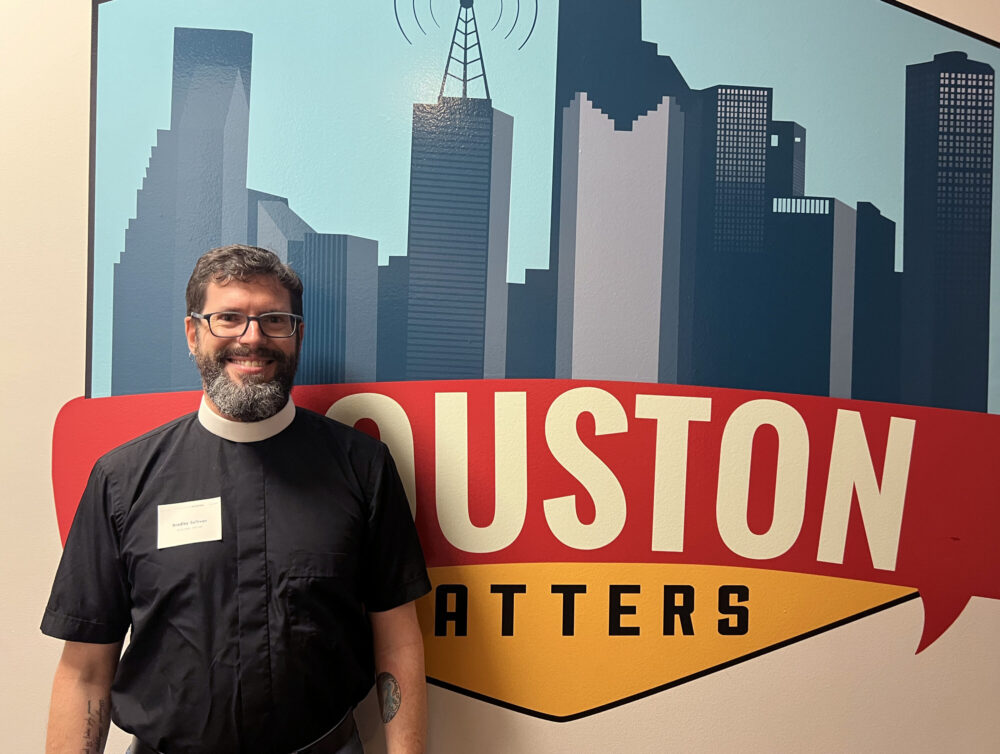 Houston Episcopal minister Rev. Bradley Sullivan poses in front of the Houston Matters logo.