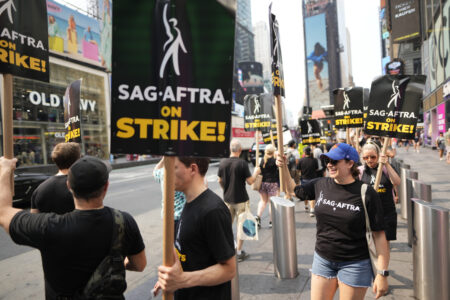 Picketers carry signs outside Paramount in Times Square on Tuesday, July 18, 2023, in New York. The actors strike comes more than two months after screenwriters began striking in their bid to get better pay and working conditions and have clear guidelines around the use of AI in film and television productions.