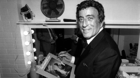 US singer Tony Bennett signs an autograph to a record in his loge on march 6, 1988 after the concert at the Stockholm "Börsen". (Photo by Bernt CLAESSON / PRESSENS BILD / AFP) (Photo by BERNT CLAESSON/PRESSENS BILD/AFP via Getty Images)