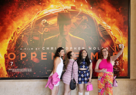 From left, Gabrielle Roitman, Kayla Seffing, Maddy Hiller and Casey Myer take a selfie in front of an "Oppenheimer" movie poster before they attended an advance screening of "Barbie," Thursday, July 20, 2023, at AMC The Grove 14 theaters in Los Angeles.
