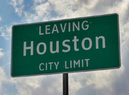 A green Houston city limit sign against a background of clouds