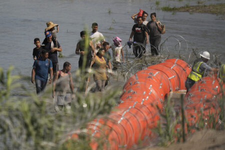 Migrants trying to enter the U.S. from Mexico approach the site where workers are assembling large buoys to be used as a border barrier along the banks of the Rio Grande near Eagle Pass , Texas, Tuesday, July 11, 2023. The floating barrier is being deployed in an effort to block migrants from entering Texas from Mexico.