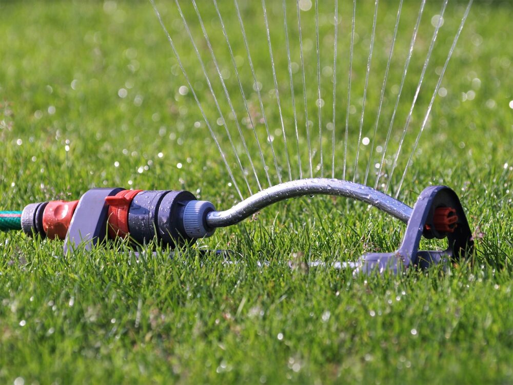 A sprinkler spraying water on a green lawn