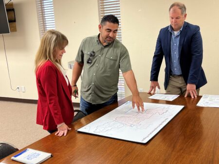 State Rep. Armando Walle (center) and Harris County Flood Control District Director Tina Petersen (left) inspect a map of proposed flood remediation projects in the Halls Bayou watershed, August 23, 2023