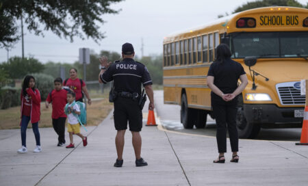 Southside Independent School District police officer Ruben Cardenas, center, keeps watch as students arrive at Freedom Elementary School, Wednesday, Aug. 23, 2023, in San Antonio. Most Texas school districts say they are unable to comply with a new law requiring armed officers on every campus. The mandate was one of Republican lawmakers' biggest acts following the Uvalde school shooting in 2022 that killed 19 children and two teachers.