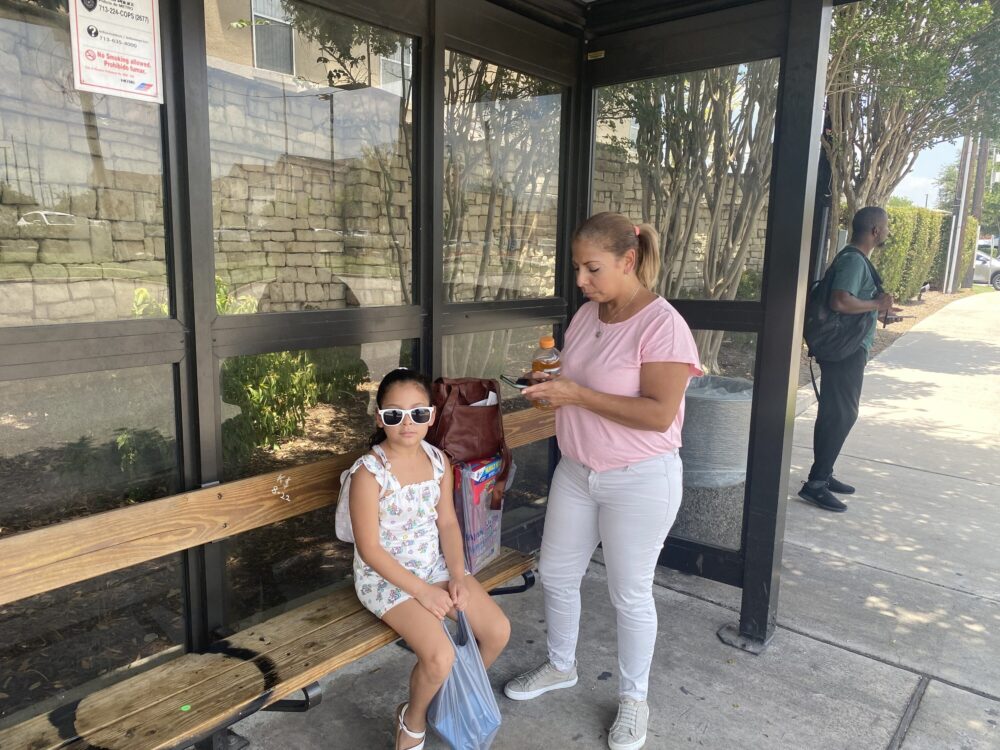 Glory Medina and her daughter at a bus shelter, July 2023.