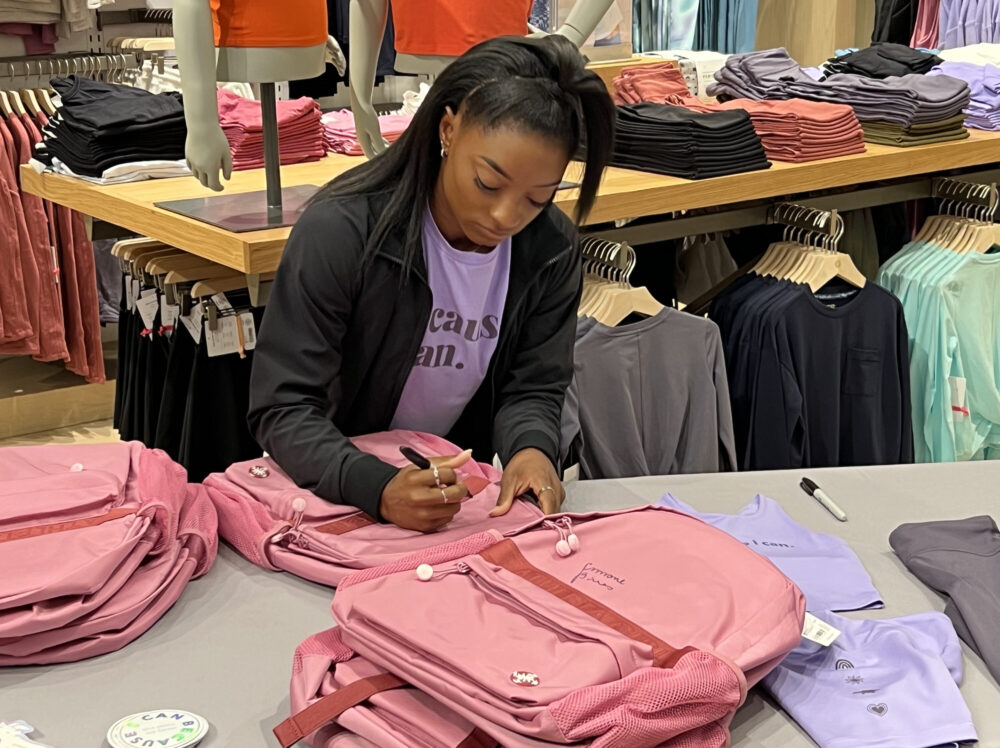 Gymnast Simone Biles autographs Athleta merchandise at an event at The Woodlands Mall on Aug. 29, 2023.
