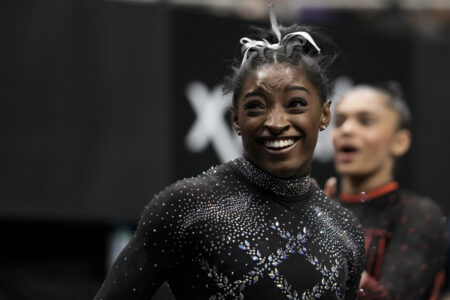 Gymnast Simone Biles smiling wearing a black-sequined leotard