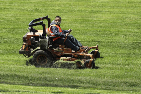 A man cuts grass on lawn mower in Waukegan, Ill., Saturday, May 2, 2020. Chicago's top health official said Saturday that people eager to get outdoors and enjoy the pleasant weather this weekend could counteract the progress against the COVID-19 pandemic made through social distancing efforts.