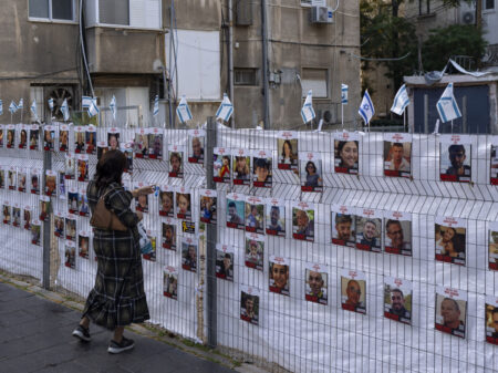 A woman looks at photographs of hostages, mostly Israeli civilians who were abducted during the Oct. 7, unprecedented Hamas attack on Israel, in Ramat Gan, Israel, Wednesday, Nov. 22, 2023. Israel and Hamas have reached an agreement for a four-day halt to the devastating war in Gaza, accompanied by the release of dozens of hostages held by the militant group in return for Palestinian prisoners jailed by Israel, mediators said Wednesday. (AP Photo/Oded Balilty)