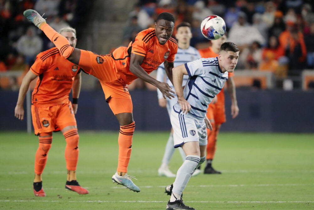 Houston Dynamo forward Ibrahim Aliyu, front left, goes up for a header over Sporting Kansas City midfielder Remi Walter, right, during the second half of an MLS playoff soccer match Sunday, Nov. 26, 2023, in Houston. (AP Photo/Michael Wyke)