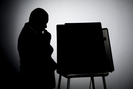 Man voting in a voting booth, silhouette shot