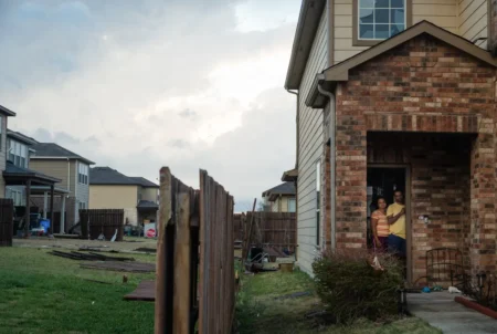 A family watches from their door as people assess damage from a tornado that struck Round Rock on March 21, 2022. As natural disasters become more severe in part due to climate change, insurance rates are rising in Texas. Credit: Evan L'Roy/The Texas Tribune