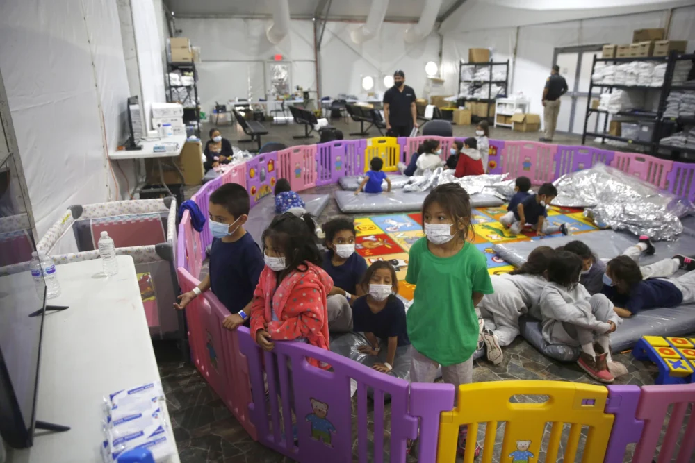 Young unaccompanied migrants, from ages 3 to 9, watch television inside a playpen at the U.S. Customs and Border Protection facility, the main detention center for unaccompanied children in the Rio Grande Valley, in Donna, Texas, in 2021.
