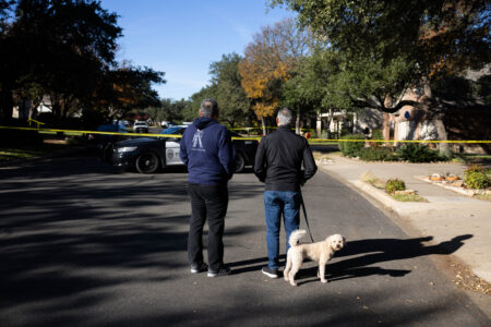 People stand behind caution tape as members of the Austin Police Department inspect the scene of a shooting in the Circle C neighborhood in Southwest Austin last month.