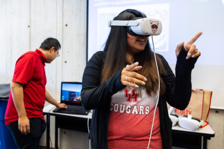 an educator points while using a VR headset in a classroom