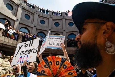 People line the railings of the outdoor rotunda at the Texas Capitol and wave signs during the "Fight for our Lives" rally in opposition of anti-LGBTQ+ bills on March 27, 2023. Credit: Evan L'Roy/The Texas Tribune