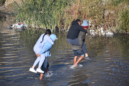 Migrants cross the Rio Grande from Ciudad Juarez to El Paso Wednesday morning. A new large group has formed just east of the downtown bridge after Texas National Guard blocked a similar entry point.