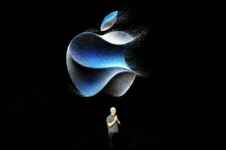 Apple CEO Tim Cook speaking in front of a large Apple logo