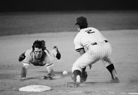 Pete Rose of the Cincinnati Reds slides into third base during a game in 1976.