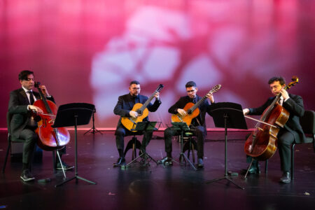 Photo of two cellists and two guitarists performing on stage