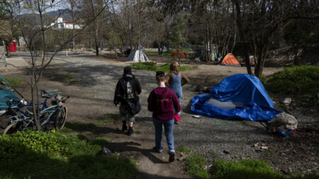 Cassy Leach, right, leads a group of volunteers to check on homeless people living in Baker Park on Thursday, March 21, 2024, in Grants Pass, Ore. (AP Photo/Jenny Kane)
