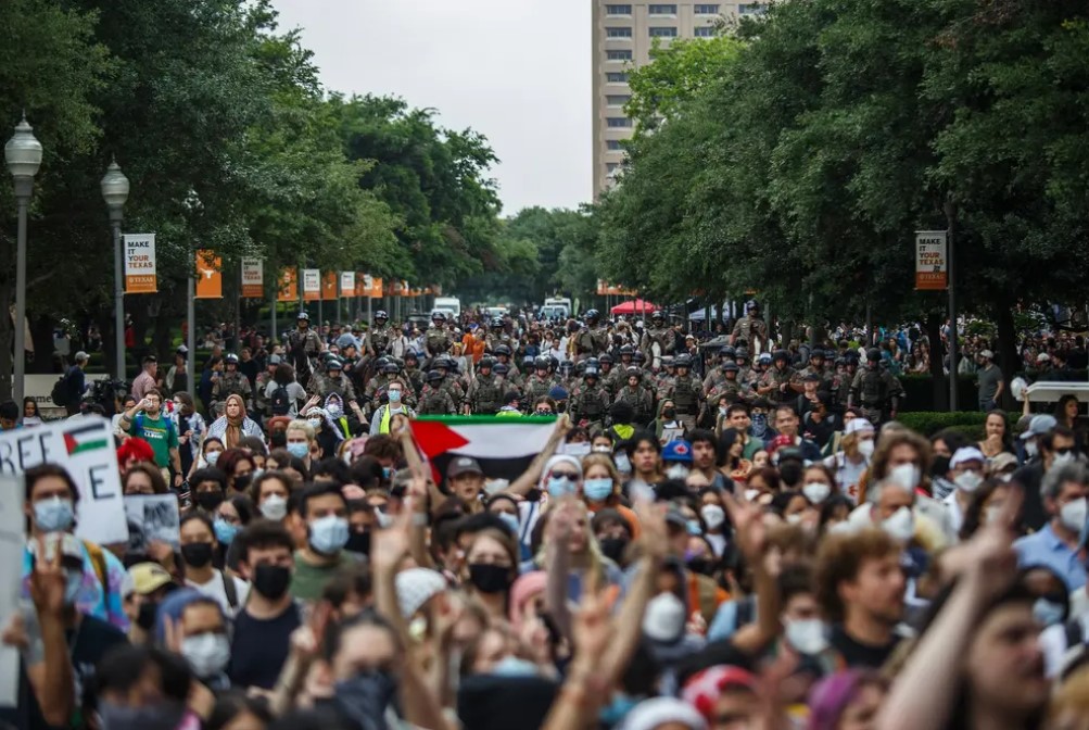 A crowd of pro-Palestinian demonstrators march Wednesday at The University of Texas at Austin. State police officers march behind them.