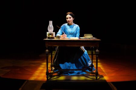 Melissa Molano writing at a desk in the play Jane Eyre
