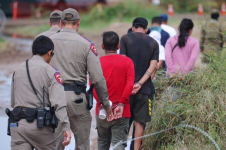 Migrants are detained in handcuffs by authorities after crossing the Rio Grande into the United States in Eagle Pass in 2023.