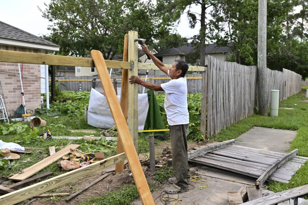 Adrian Hermamdez repairs his fence after it was destroyed by Hurricane Beryl in Houston, Wednesday, July 10, 2024. (AP Photo/Maria Lysaker)