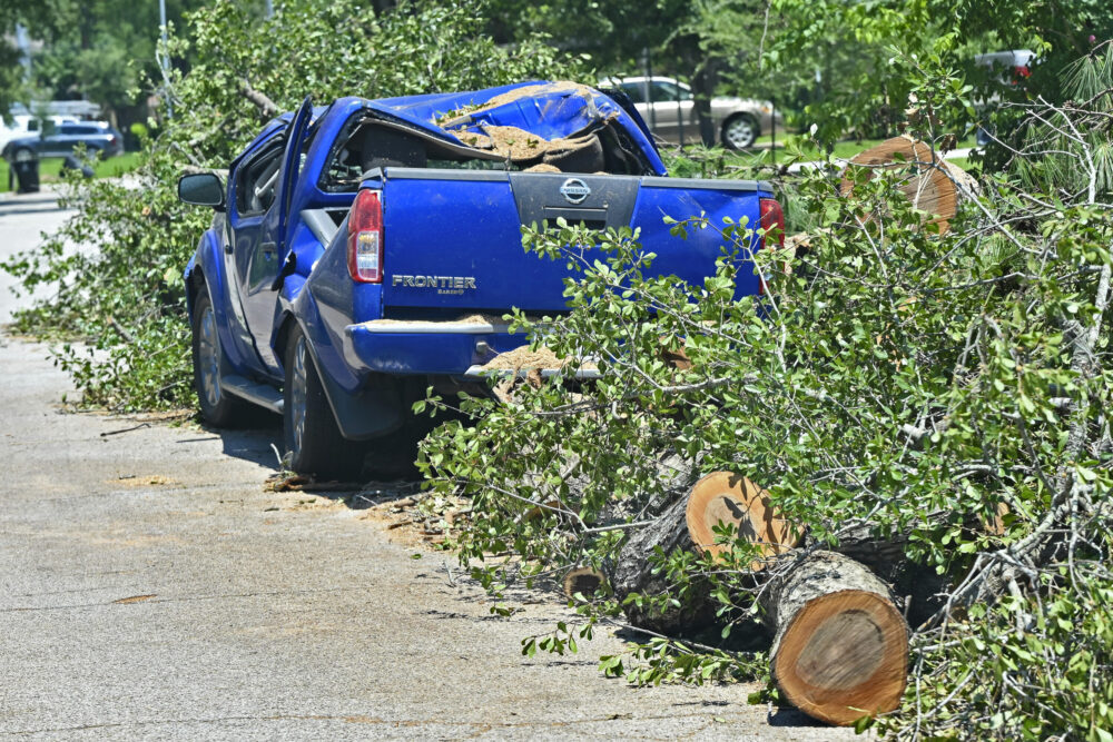 Debris from fallen trees along the road in Houston surrounds a pickup truck damaged during Hurricane Beryl.