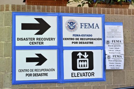 signs in Spanish and English indicating where to apply for FEMA aid.