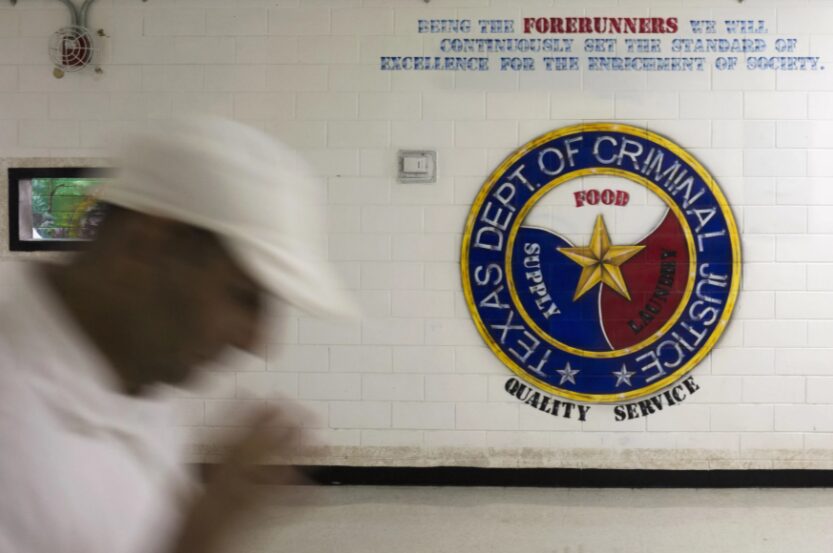 An offender walks past a sign on a wall at the the Darrington Unit of the Texas Department of Criminal Justice men's prison in Rosharon, Texas, in 2014.