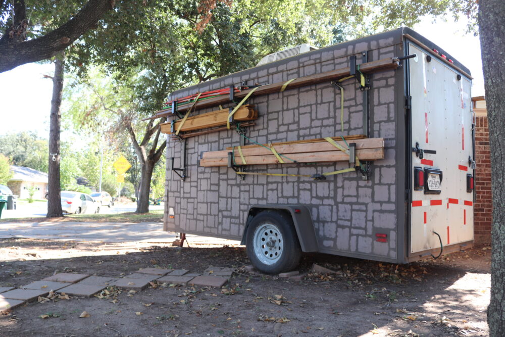 a trailer set on an unpaved portion of a front yard. 