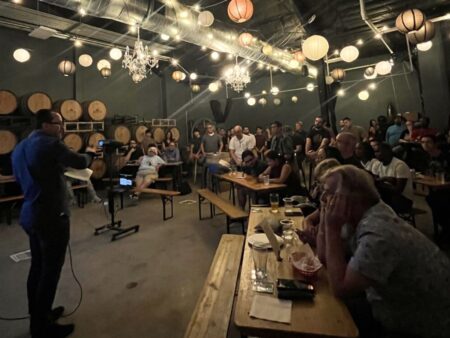 People in a brewery listen to a man speaking