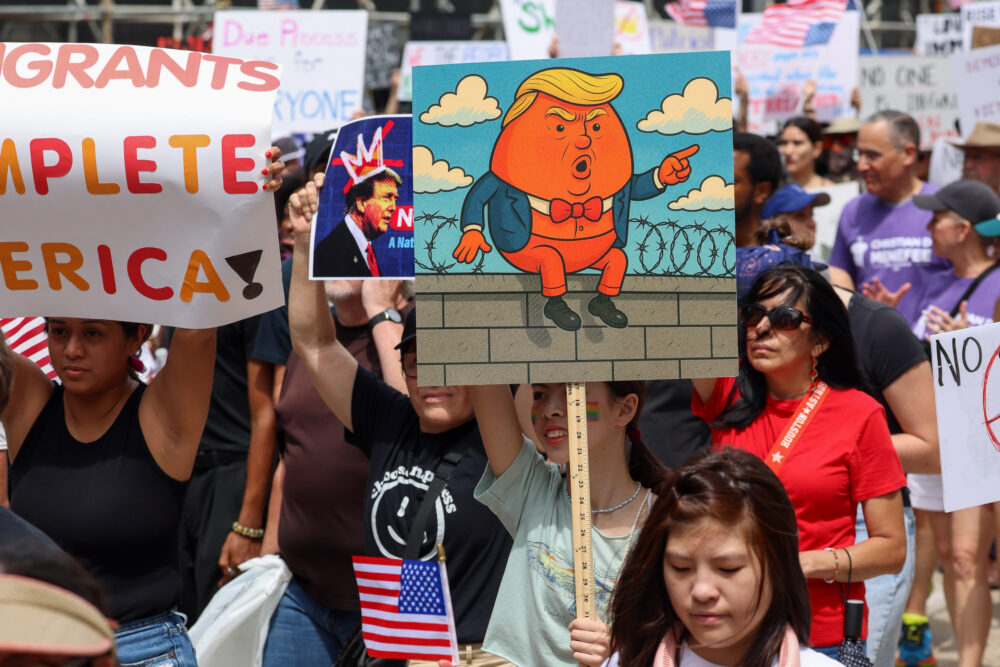 Seorang pemrotes memiliki sinyal dengan kartun Presiden Donald Trump pada hari Sabtu, 14 Juni 2025 di Houston. (Kredit Foto: Rob Salinas/Houston Public Media)