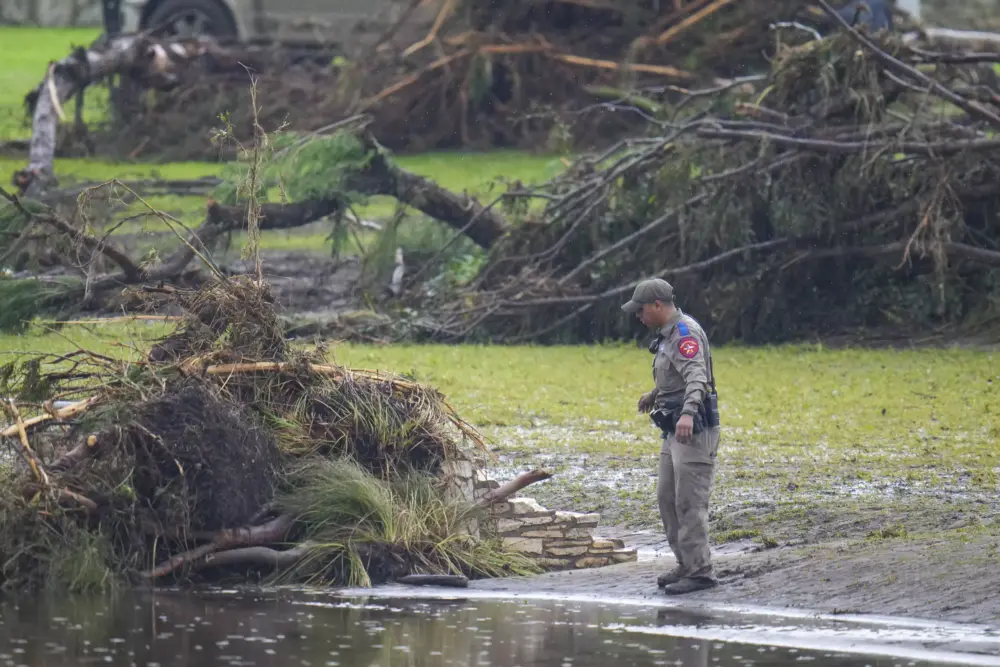 A Texas Department of Public Safety official inspects debris on the waterfront at Camp Mystic along the banks of the Guadalupe River after a flash flood swept through the area Sunday, July 6, in Hunt, Texas.