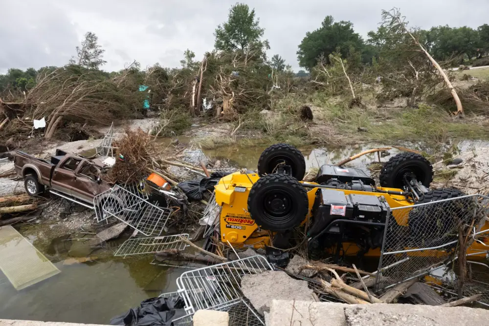Trucks are tilted over at Louise Hays Park in Kerrville due to heavy rainfalls that caused flooding along Guadalupe River on Sunday, July 6, 2025. Law Enforcement workers and volunteers are in the work of clearing up debris from the flooding.