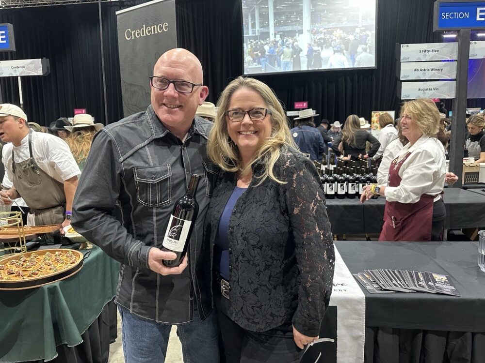 Tom and Whitney Kilgore pose with a bottle of wine from their business, 5 Fifty-Five Vineyard and Winery, at the Houston Livestock Show and Rodeo's annual Rodeo Uncorked! Roundup & Best Bites Competition. (Photo Credit: Natalie Weber / Houston Public Media)