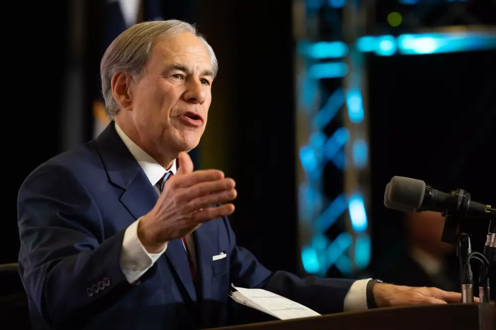 A man gestures with his hand as he speaks at a podium.