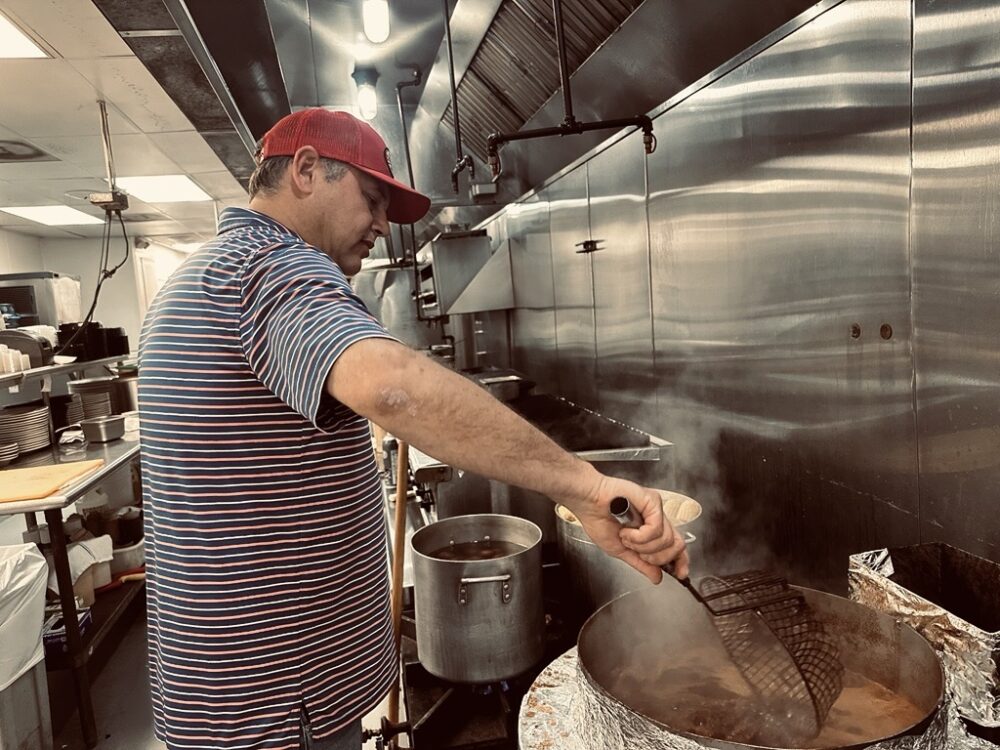 Dominic Mandola, owner of the Ragin’ Cajun in Houston, demonstrates how crawfish are cooked at his restaurant on Tuesday, April 14, 2026. (Photo Credit: Natalie Weber / Houston Public Media)