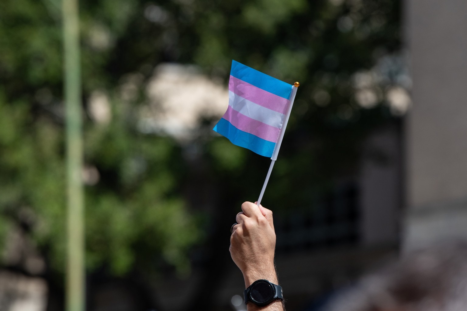 An attendee waves a trans pride flag while marching with activists and supporters from the Bexar County Courthouse to Crockett Park in